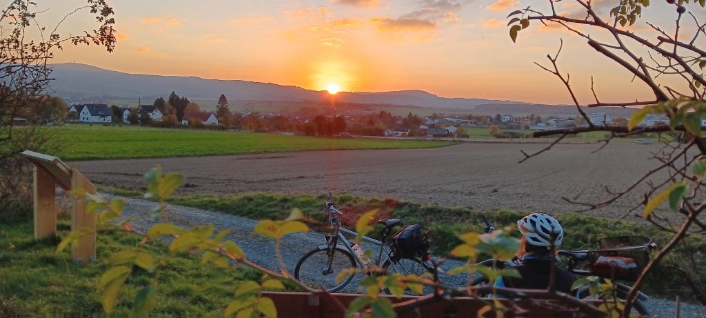 Eine Radfahrerin blickt in den Sonnenuntergang