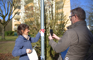 Foto von zwei Personen, die einen Aufkleber an einem Mast anbringen